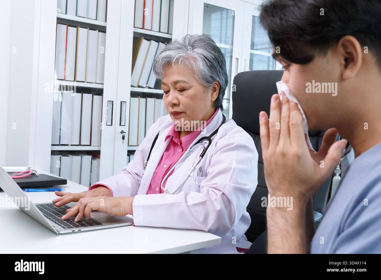 Médecin spécialiste senior des allergies féminines en asie consultant le patient masculin dans la clinique hospitalière moderne, consultation médicale et conseils de traitement, soins de santé Banque D'Images