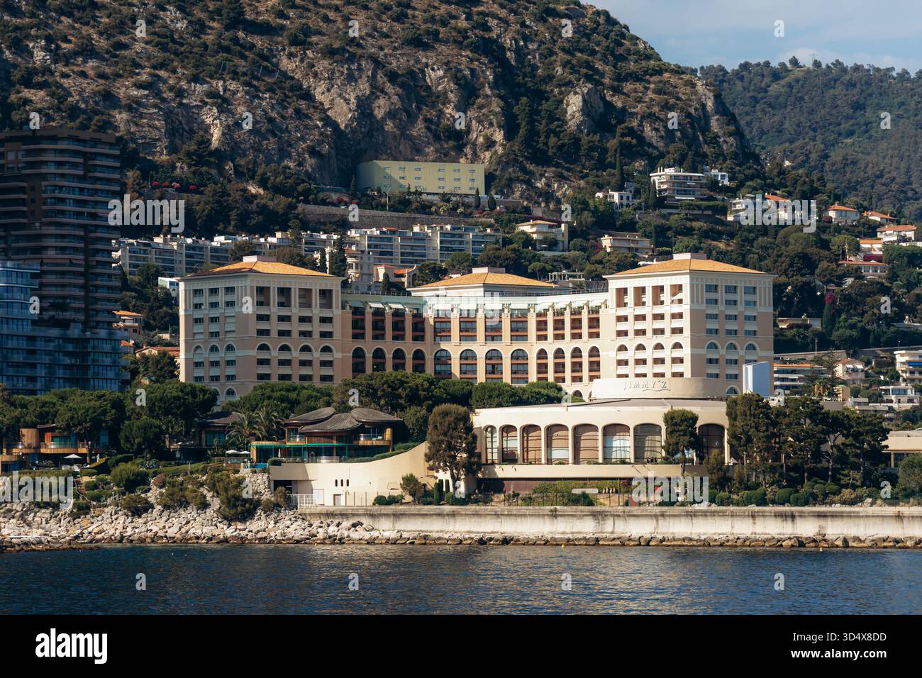Monaco, Monaco - 28 juin 2025 : Monte Carlo Bay Hotel and Resort sur le front de mer avec collines et bâtiments résidentiels en arrière-plan Banque D'Images