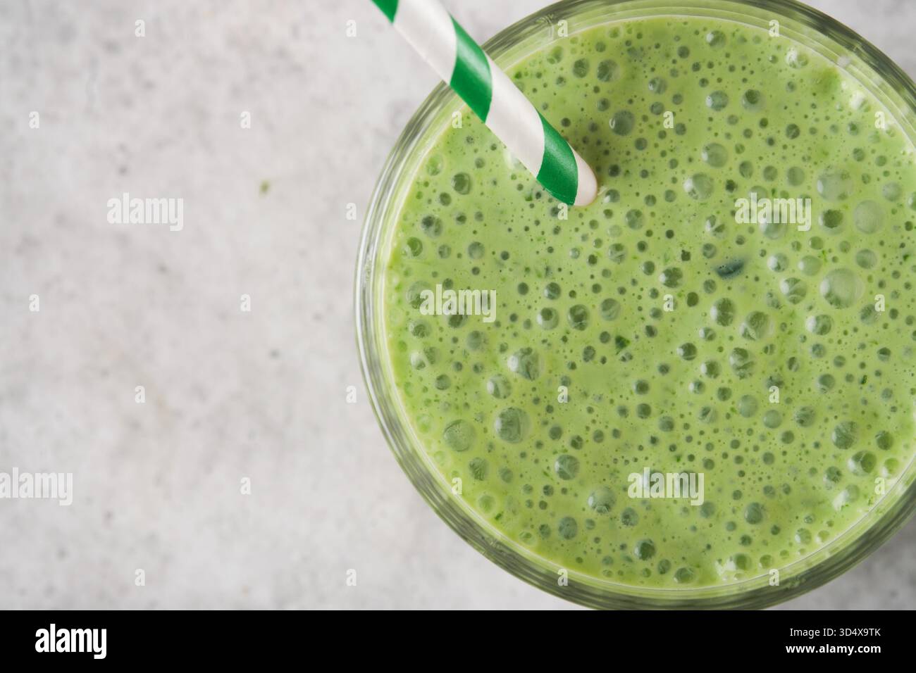 Smoothie aux épinards vert sain. Smoothie végétalien ou milkshake à partir d'épinards, de bananes et de graines de chia sur fond de table en béton gris. Manger propre, régime alcalin. Vue de dessus. Maquette. Banque D'Images