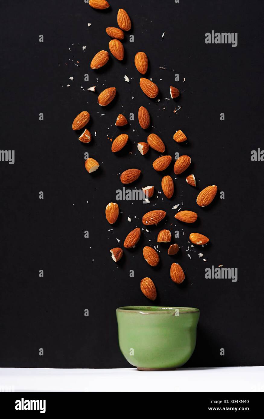 Amandes tombant dans un petit récipient Banque D'Images