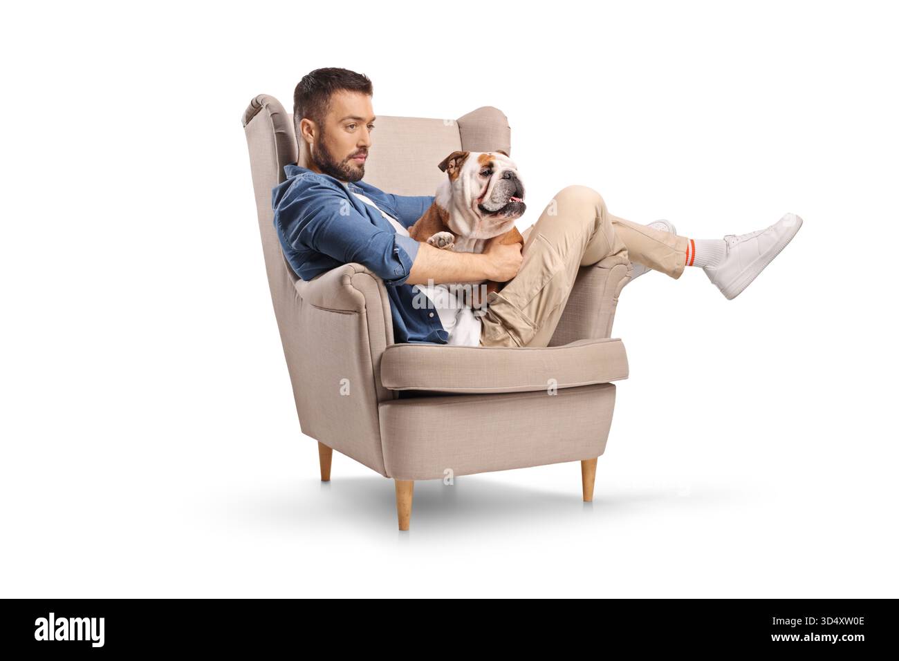 Jeune homme se reposant dans un fauteuil avec son chien isolé sur fond blanc Banque D'Images