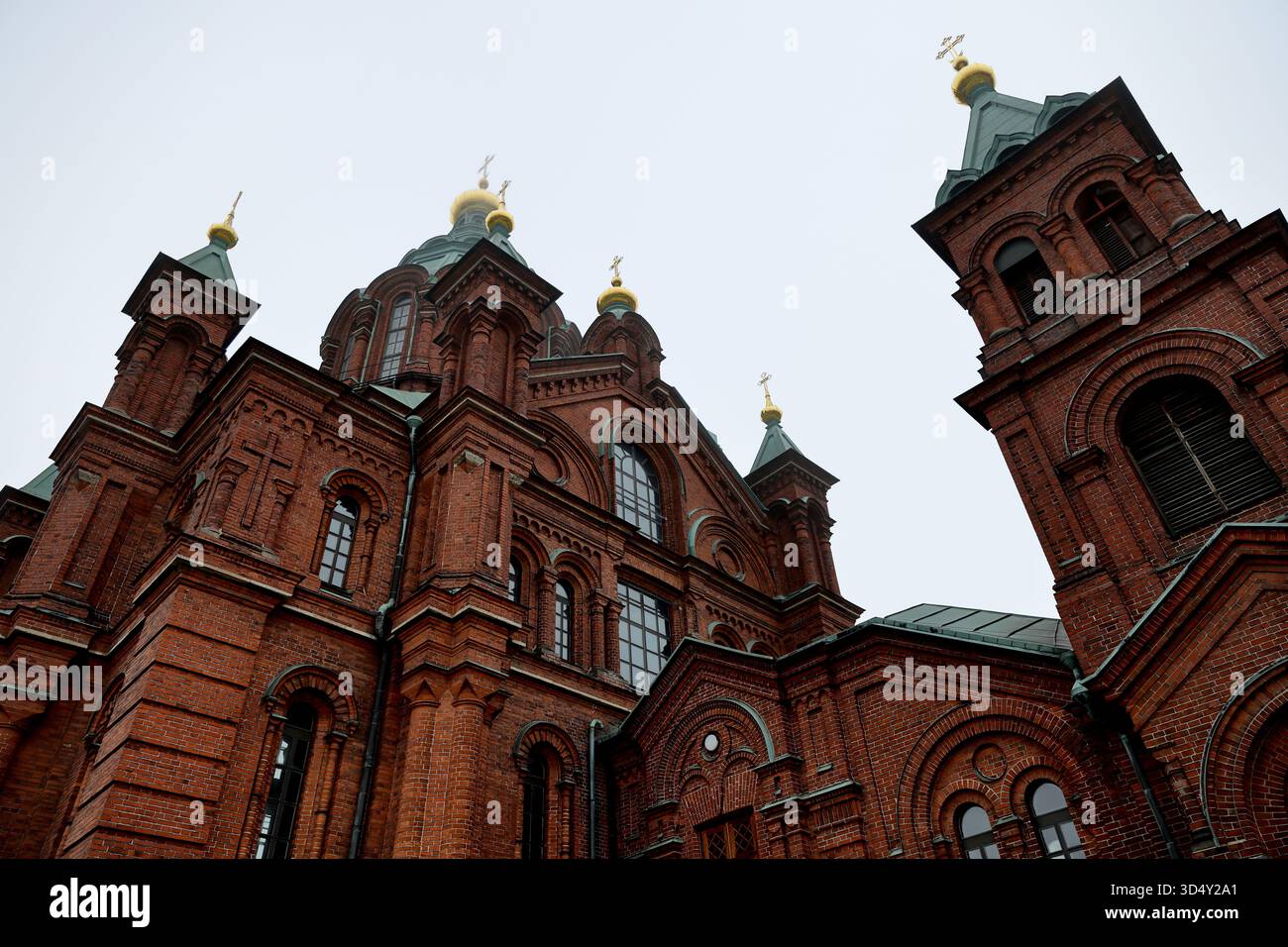 Vue rapprochée de la maçonnerie de la cathédrale d'Uspenski avec fenêtres cintrées, tambour en cuivre, croix dorées et dômes en oignon à Helsinki, Finlande, sous un ciel blanc. Banque D'Images