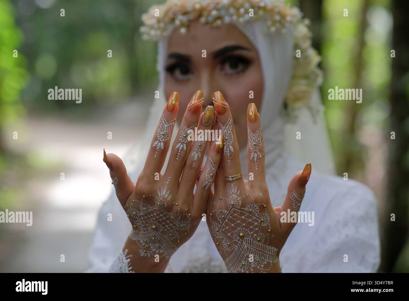 Une mariée montre ses mains qui ont été joliment décorées avec du henné ou des tatouages temporaires. Banque D'Images