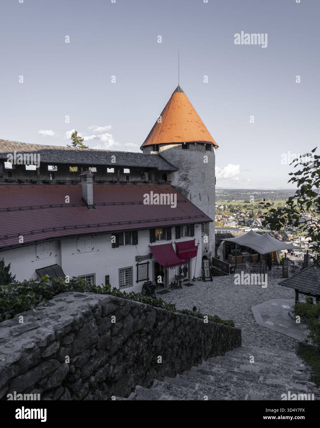 Vue sur les anciennes marches en pierre mènent à un château médiéval avec un toit conique orange vibrant, Bled, Radovljica, Slovénie. Banque D'Images