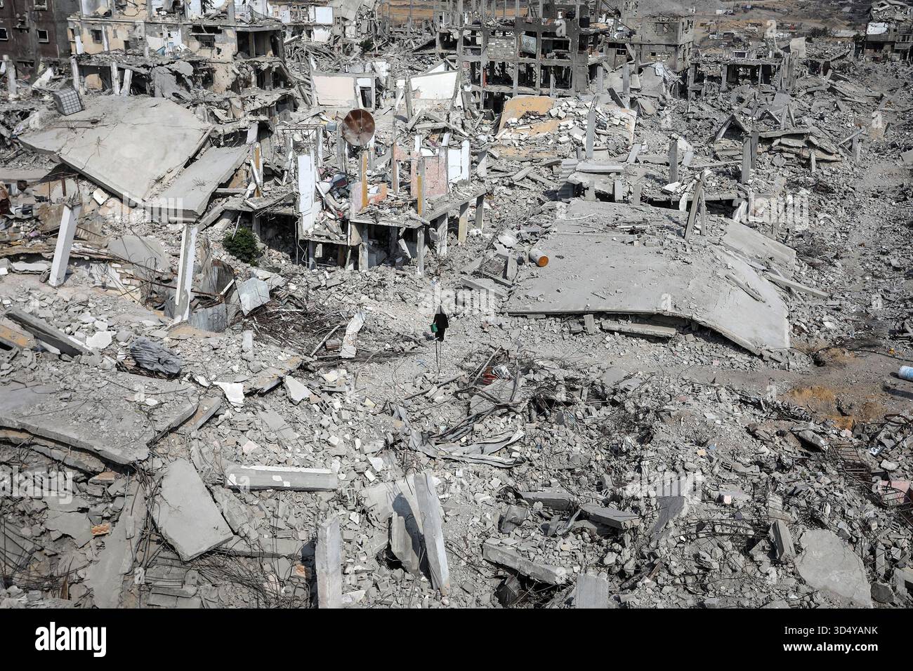 Khan Yunis, Territoires palestiniens. 11 novembre 2025. Une palestinienne traverse les ruines de bâtiments détruits dans la zone d'Al-Katiba à Khan Younis. Les Palestiniens déplacés tentent de rentrer chez eux après le retrait de l’armée israélienne de la ville. Crédit : Abed Rahim Khatib/dpa/Alamy Live News Banque D'Images