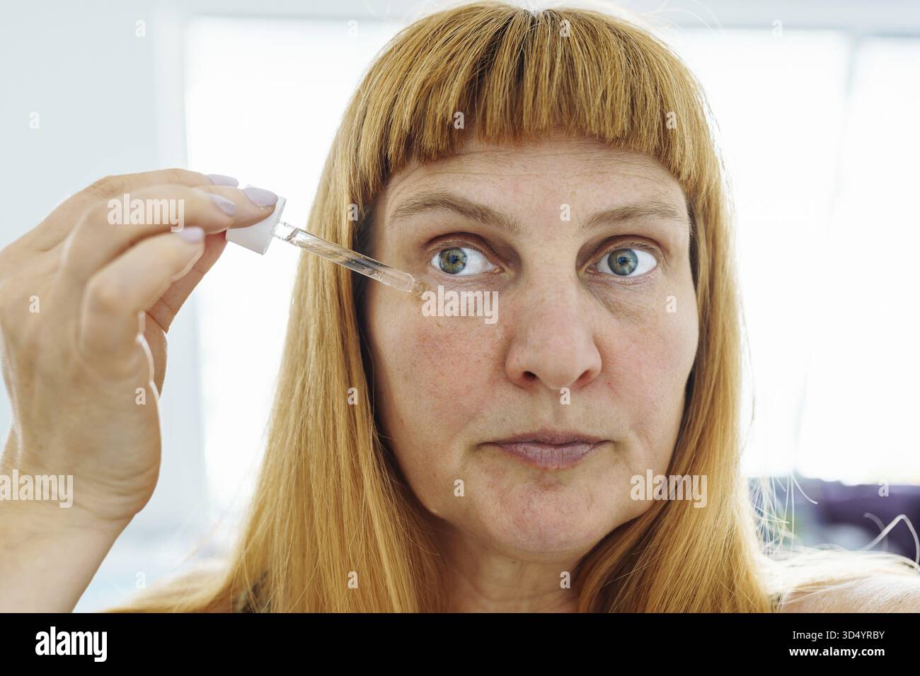 Visage femme d'âge moyen gros plan, blonde, application de produit cosmétique contre le vieillissement de la peau, visage, contre les rides sous les yeux Banque D'Images