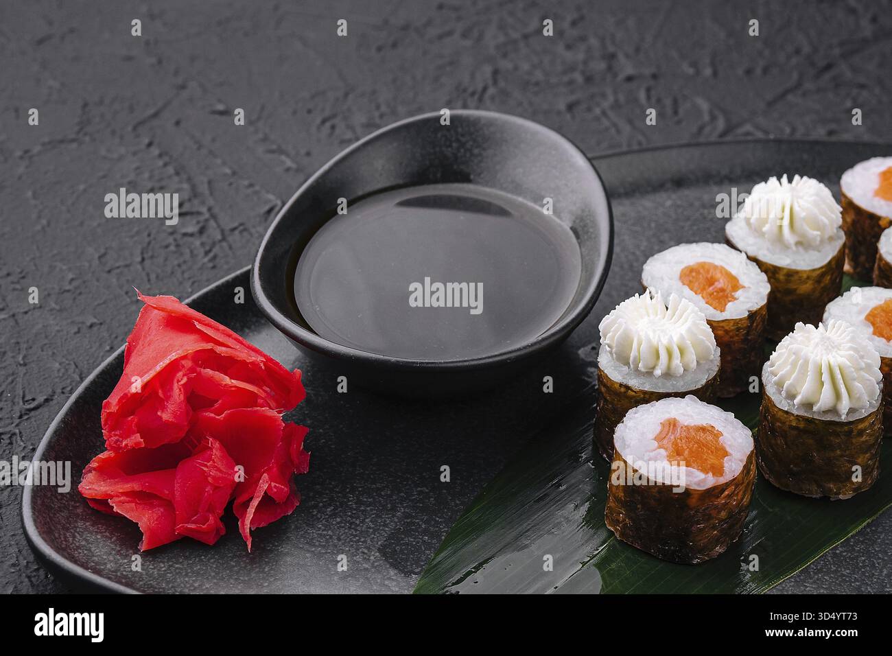 Nourriture, sushi avec fromage Philadelphie et saumon sur assiette asiatique noire Banque D'Images