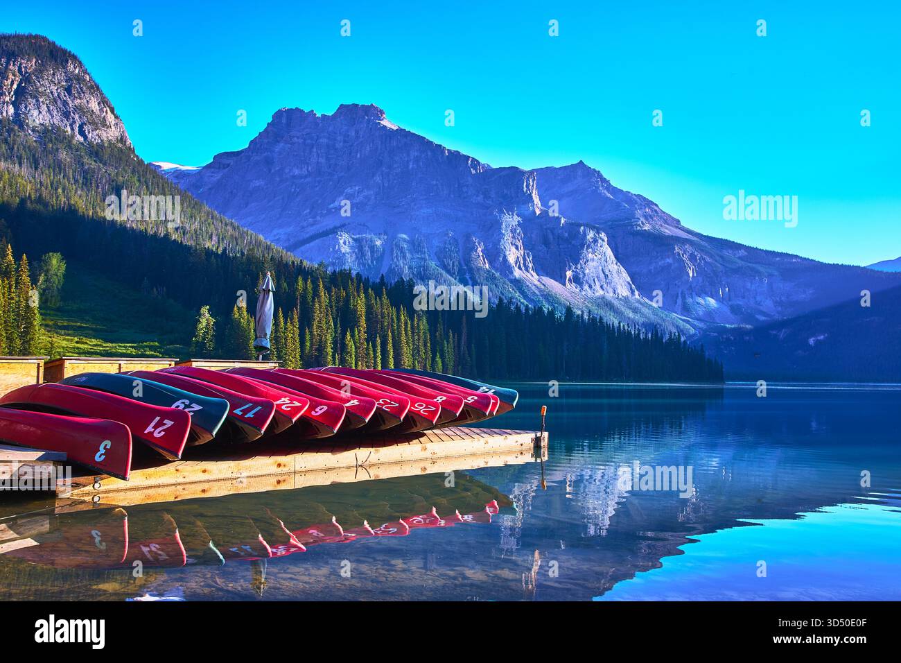 Canoës et quai en bois sur le lac de montagne immaculé avec des pics alpins spectaculaires reflétés Banque D'Images