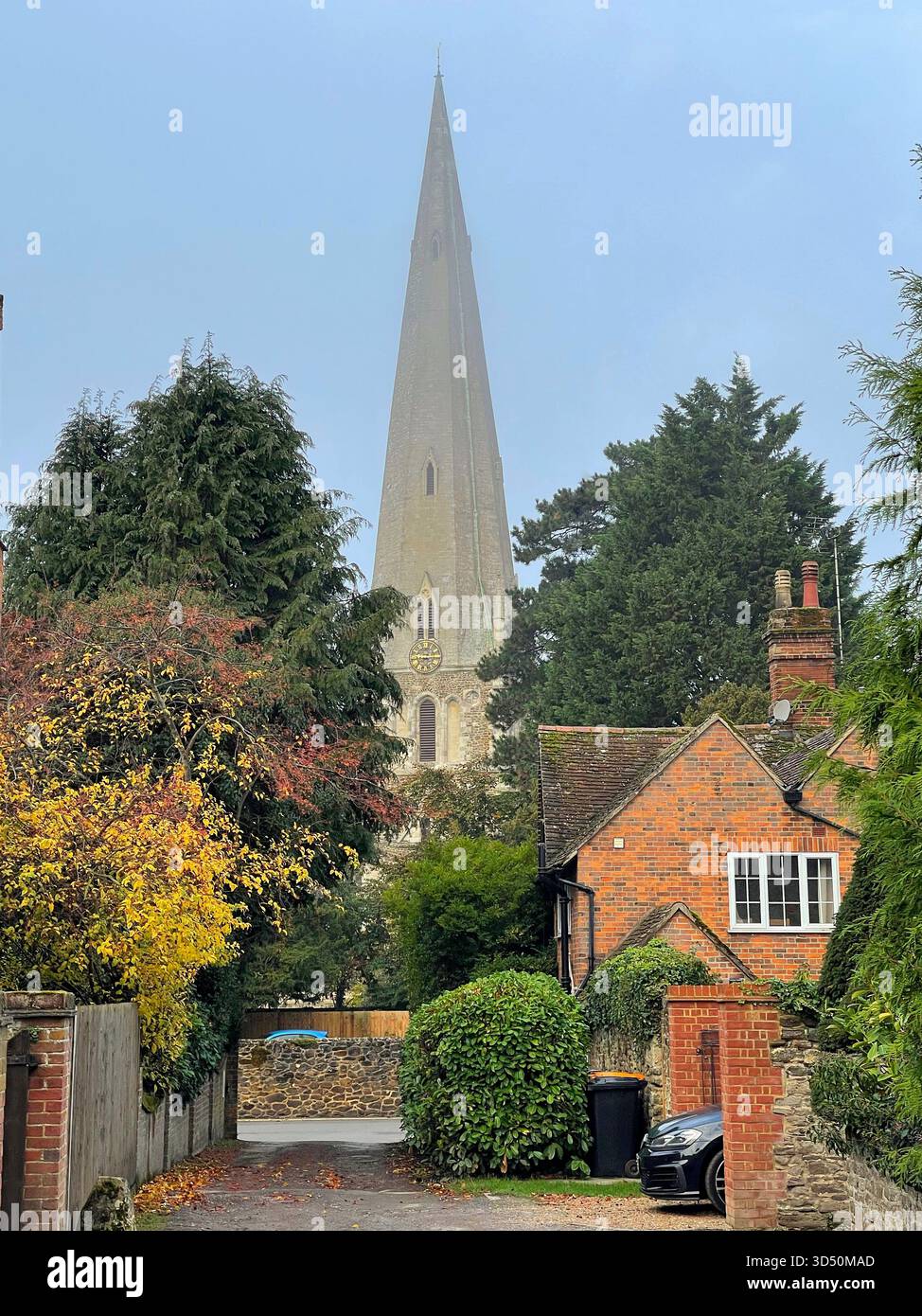 Rue résidentielle à Leighton Buzzard, Bedfordshire, avec des arbres d'automne et la flèche de l'église All Saints s'élevant en arrière-plan Banque D'Images