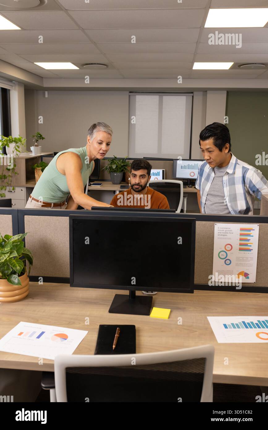 Collaboration de divers collègues examinant les données dans une armoire de bureau, avec des moniteurs et des graphiques Banque D'Images