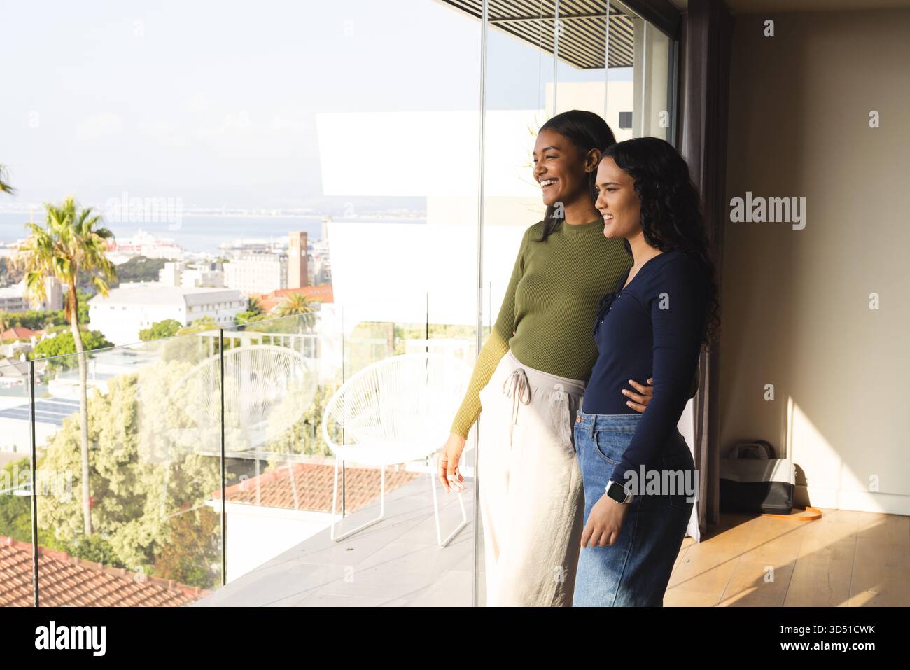 Diverses amies féminines regardant à travers les portes vitrées aux chaises de balcon dans le salon, espace de copie Banque D'Images