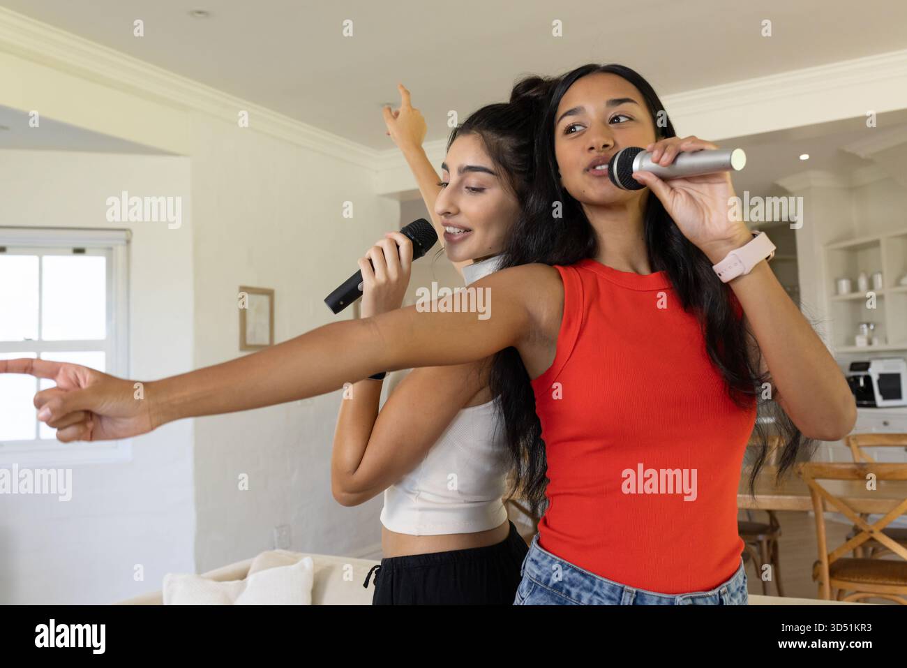 Chanter diverses amies debout dos à dos dans un salon ouvert, avec des microphones Banque D'Images