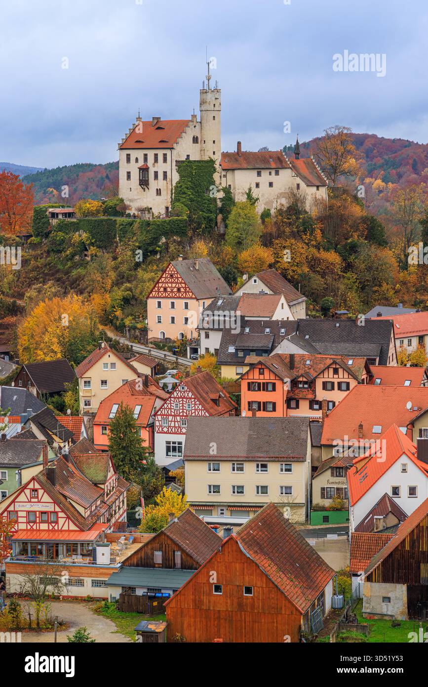 Image verticale du château de Gößweinstein en Suisse franconienne, Bavière, Allemagne, entouré par un feuillage d'automne vibrant sous un ciel fortement couvert. Banque D'Images