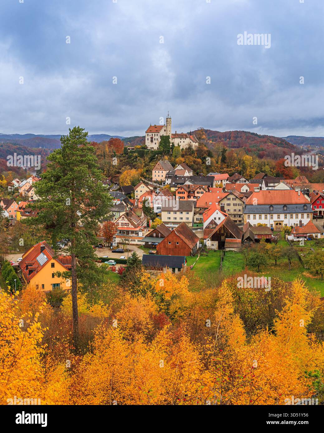 Image verticale du château de Gößweinstein en Suisse franconienne, Bavière, Allemagne, entouré par un feuillage d'automne vibrant sous un ciel fortement couvert. Banque D'Images