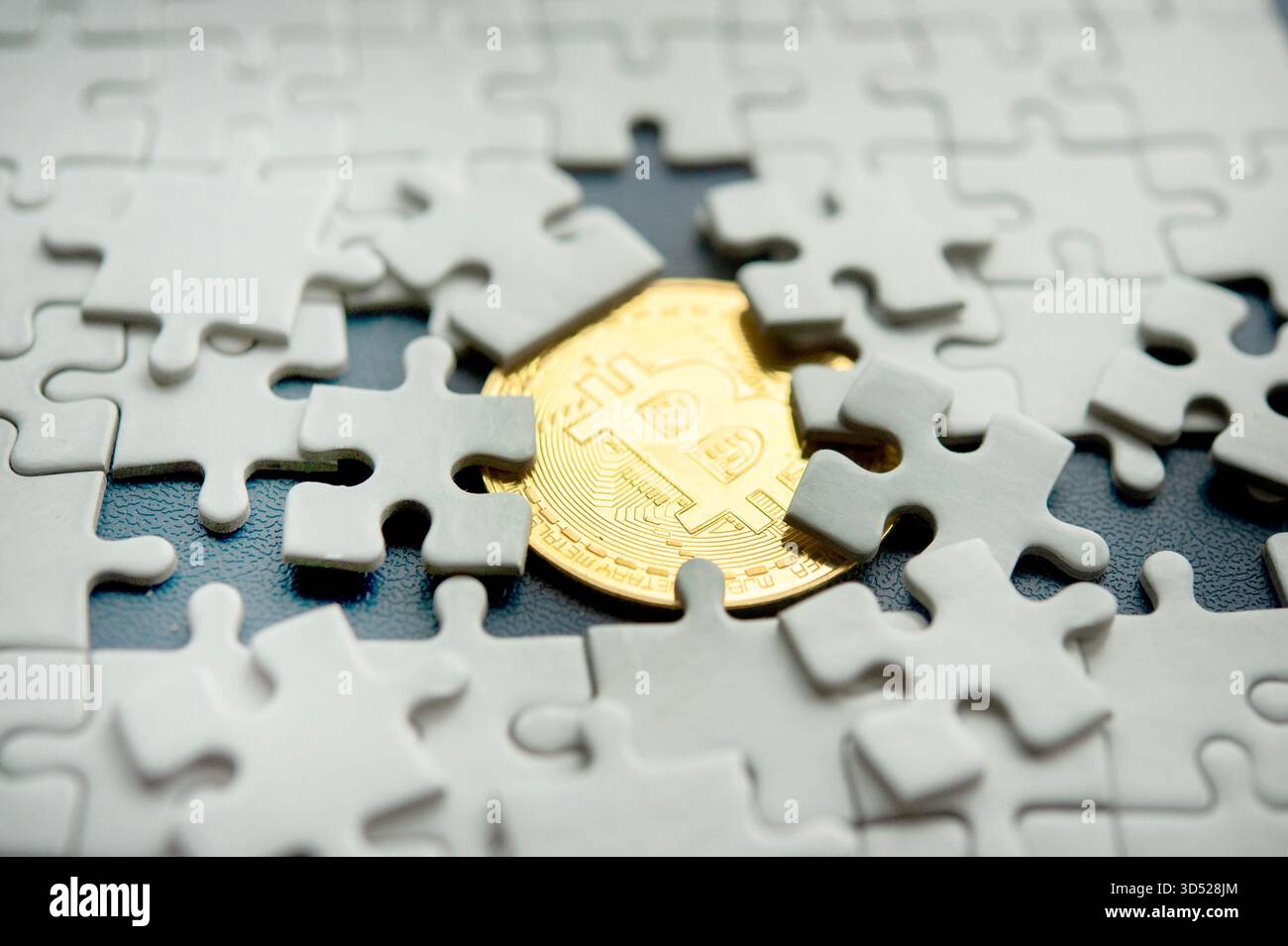 Bitcoin coin partiellement caché sous des pièces de puzzle dispersées représentant la complexité de la crypto-monnaie Banque D'Images