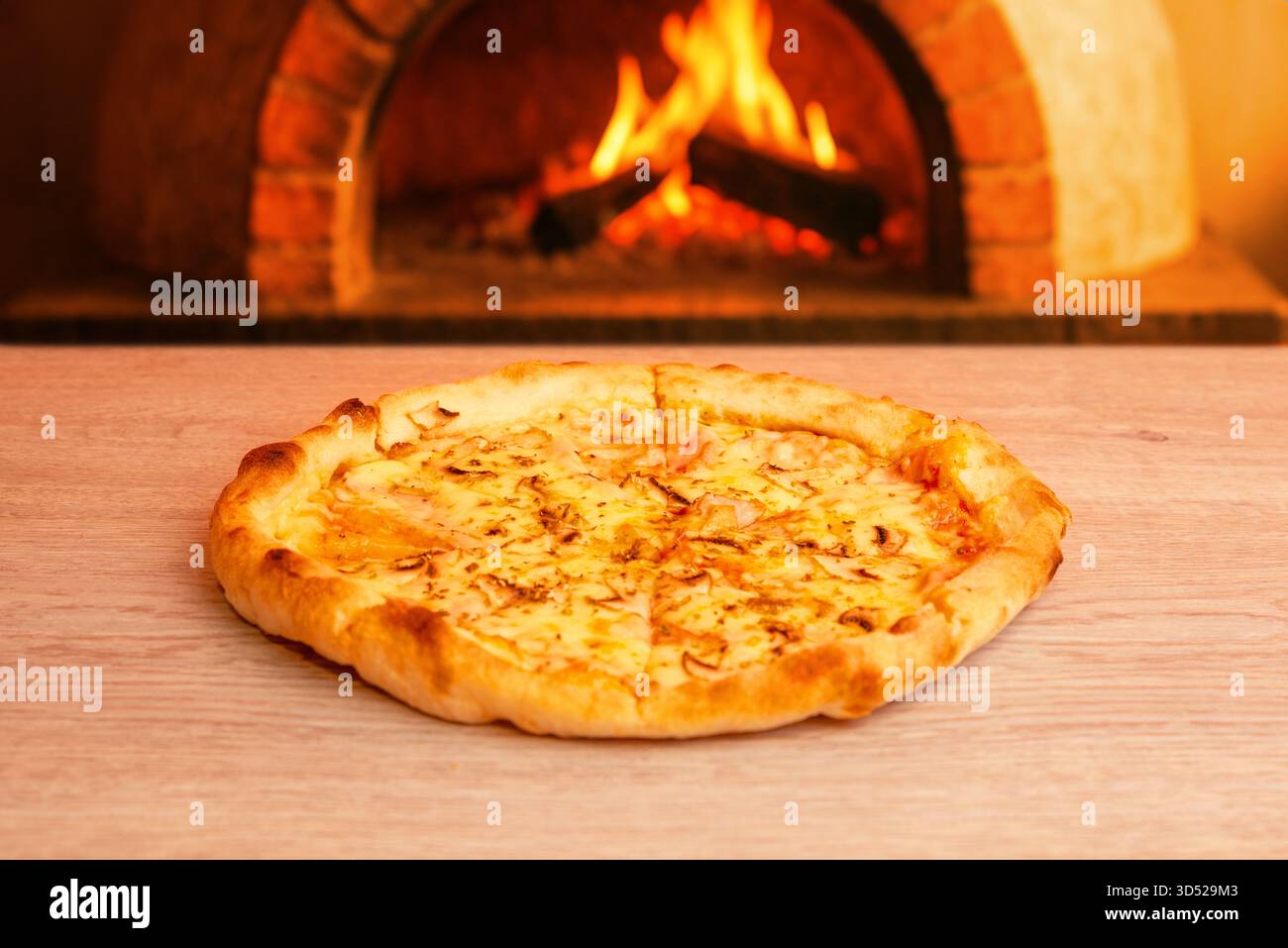 Savoureuse pizza chaude devant le four traditionnel en brique au feu de bois, ambiance de restaurant confortable avec flamme et chaleur Banque D'Images