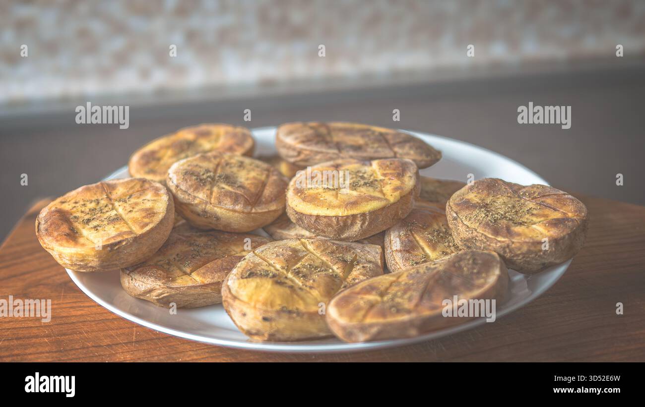 Quartiers de pommes de terre dorés au four avec des épices sur une plaque en céramique, vue de haut en bas pour la photographie de nourriture rustique Banque D'Images