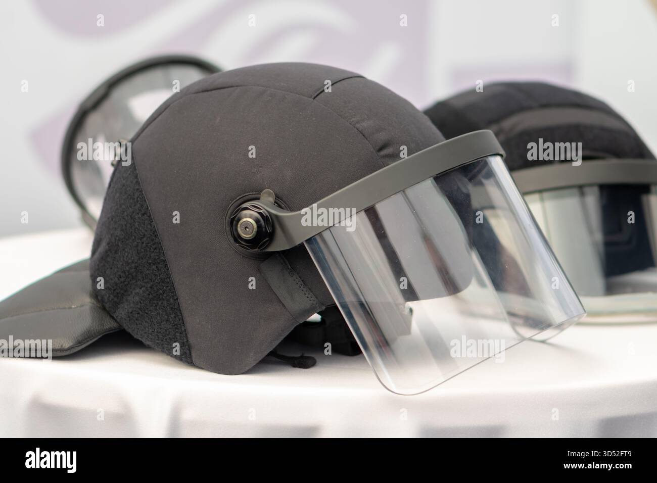 Un casque de police avec une grande visière transparente est situé sur la table à côté d'un autre casque de protection Banque D'Images