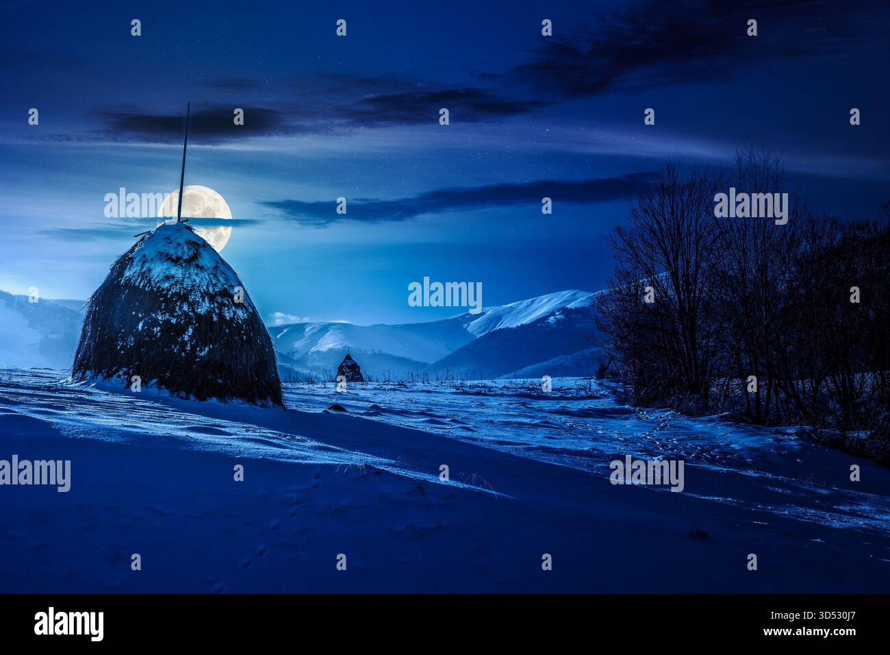 paysage rural avec botte de foin en hiver la nuit. paysage de campagne avec colline enneigée dans les montagnes en pleine lune. vue en angle bas avec neige Banque D'Images