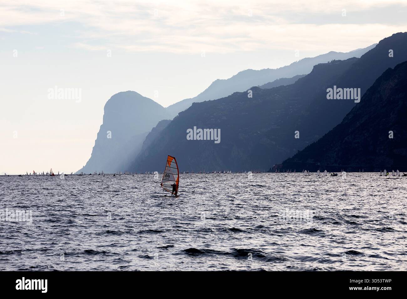 Kitesurfeurs et wingfoileurs profitant d'excellentes conditions venteuses pour les sports nautiques sur le spectaculaire lac de Garde dans la région nord de l'Italie. Banque D'Images