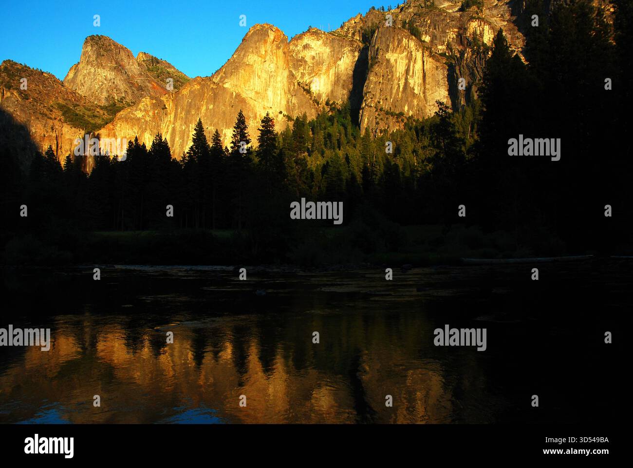 Un sommet de la chaîne de montagnes Cathedral Rocks se reflète dans les eaux calmes de la rivière Merced dans le parc national de Yosemite Banque D'Images