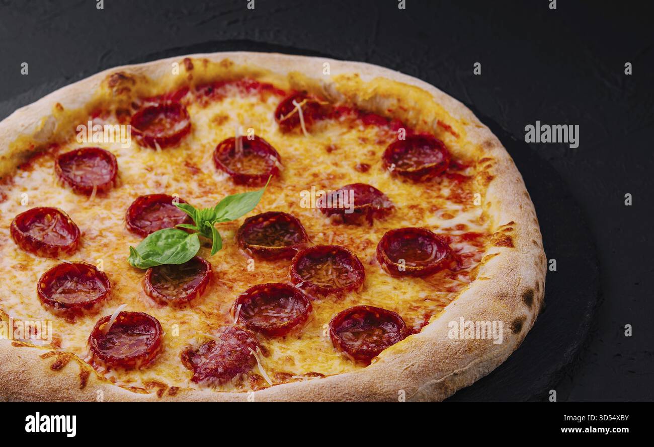 Nourriture, pizza au pepperoni au basilic et au parmesan sur une assiette en pierre noire Banque D'Images