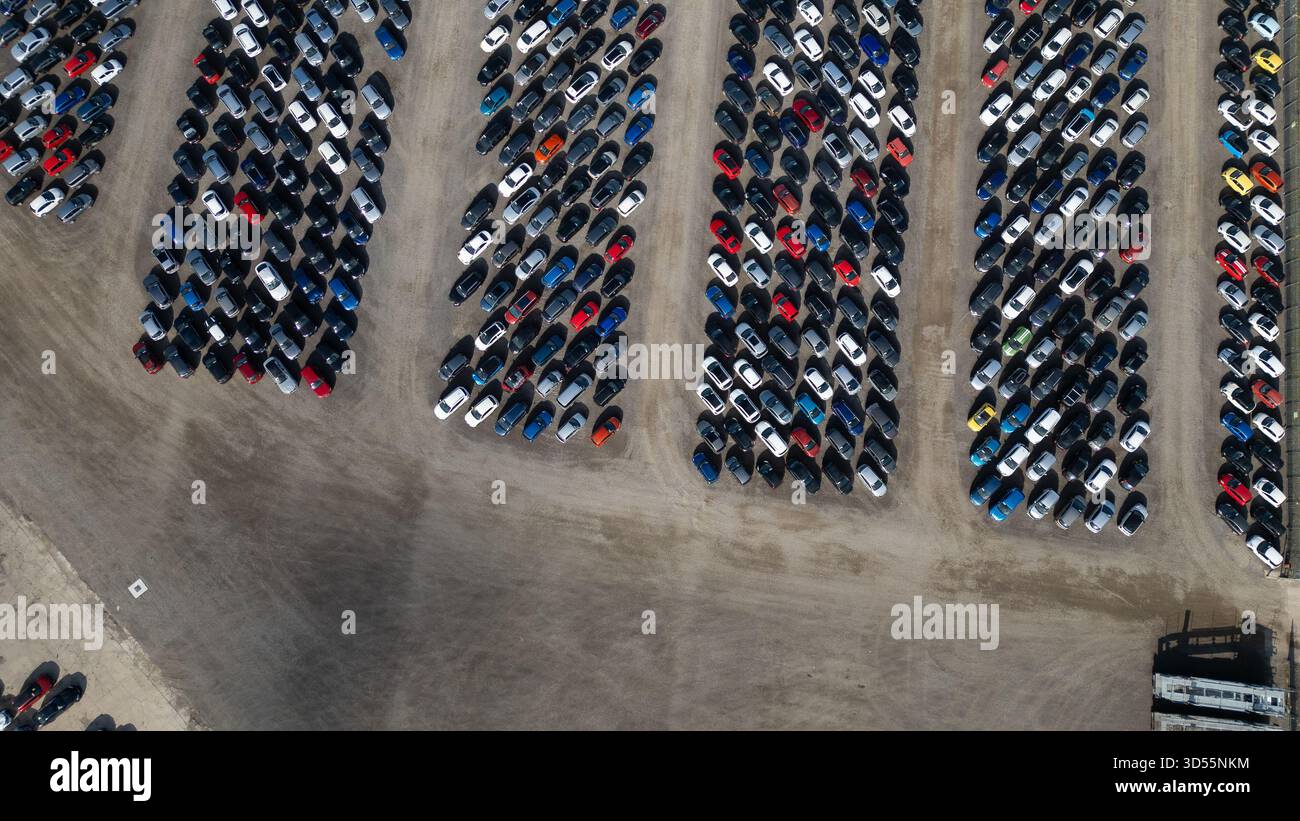 Vue aérienne d'un grand terrain rempli de rangées de voitures garées de différentes couleurs et tailles, étroitement emballées ensemble sur un terrain de terre à Copart yard, York Banque D'Images
