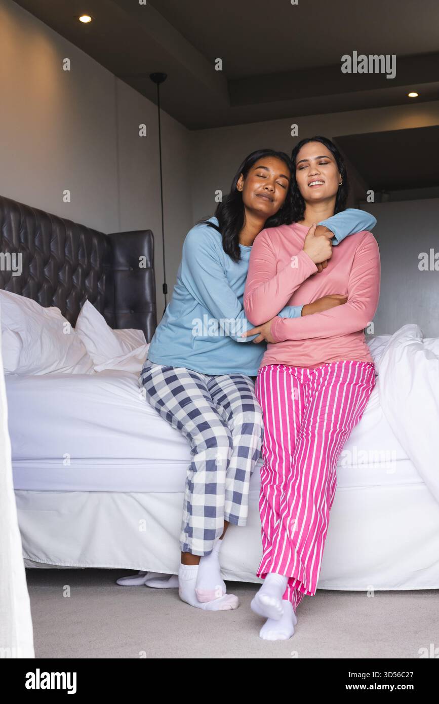 Embrasser divers partenaires féminins assis sur le lit dans une chambre moderne, avec lampadaire luisant Banque D'Images
