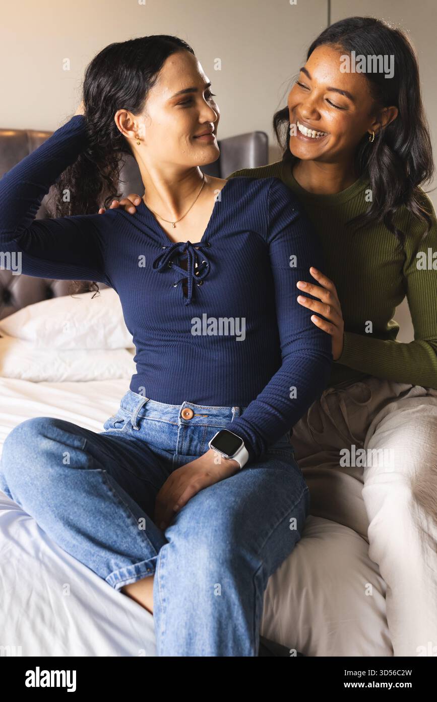 Partager un moment affectueux deux femmes assises sur le lit dans la chambre, avec smartwatch et oreillers Banque D'Images