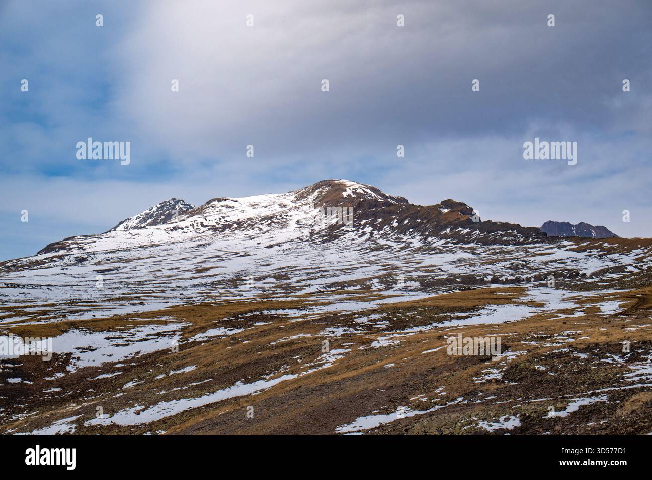 Une montagne couverte de neige et un ciel nuageux. Le ciel est bleu et la neige blanche Banque D'Images