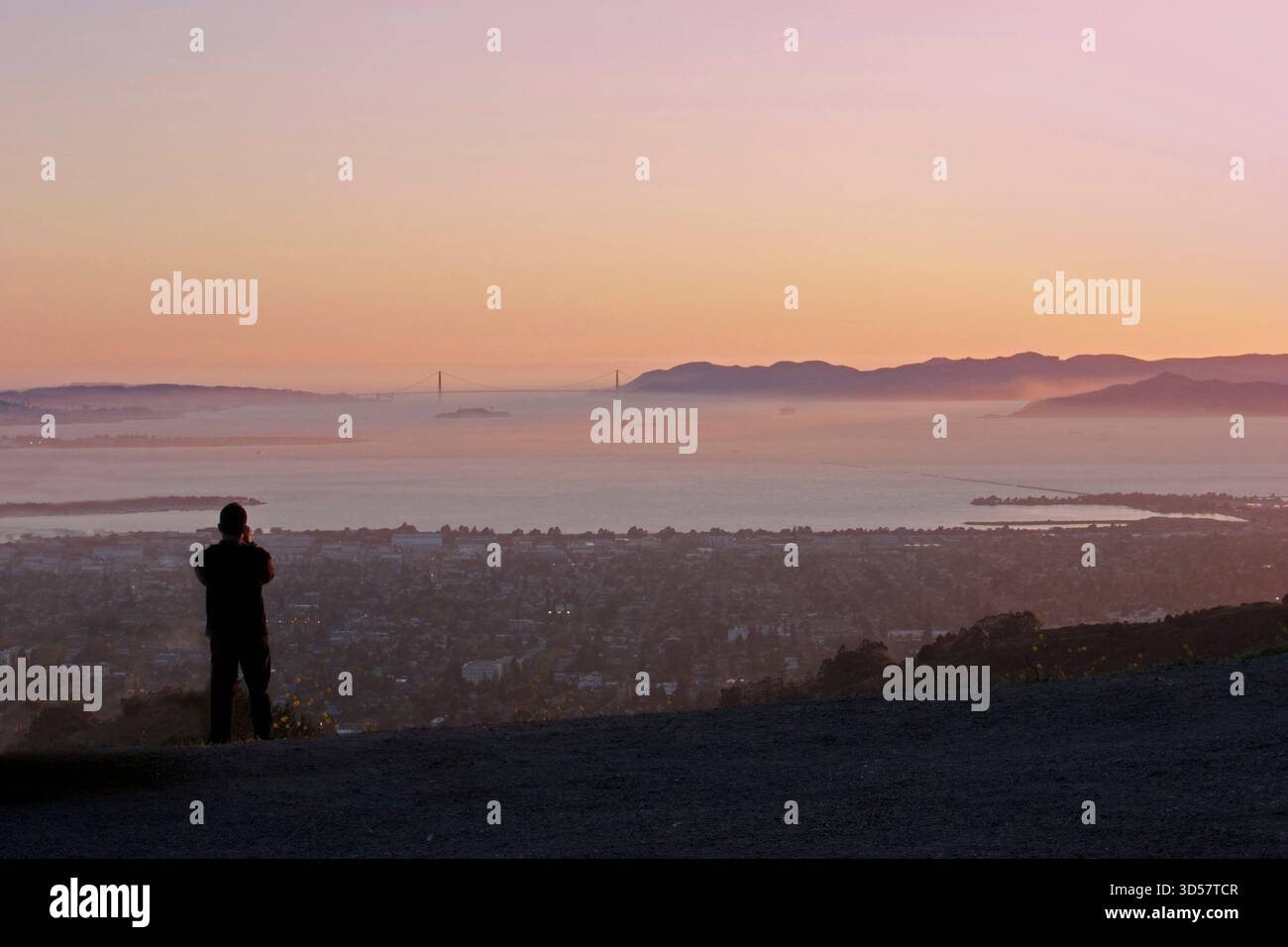 Silhouette vue arrière d'un homme regardant la vue de la ville et le Golden Gate Bridge dans la distance un jour brumeux, San Francisco, Californie, États-Unis Banque D'Images