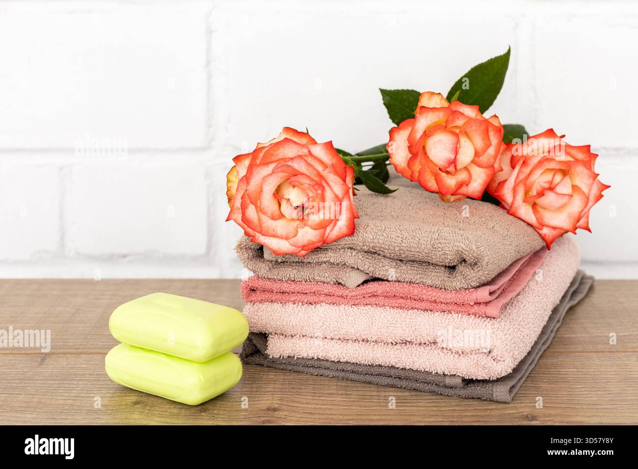 Composition spa avec serviettes éponge douces, fleurs de rose rouge et savon sur le parquet. Banque D'Images