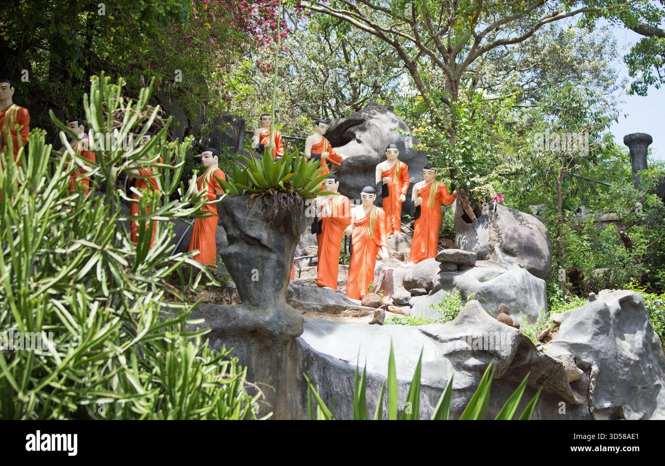 Modèles de moines bouddhistes en costume orange marchant à travers une rocaille paysagée au Sri Lanka Banque D'Images