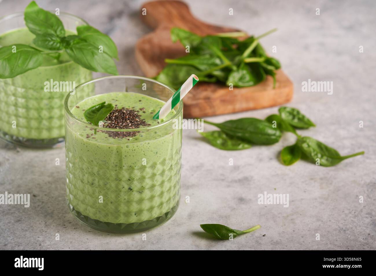 Smoothie aux épinards vert sain. Smoothie végétalien ou milkshake à partir d'épinards, de bananes et de graines de chia sur fond de table en béton gris. Manger propre, régime alcalin. Vue de dessus. Maquette. Banque D'Images