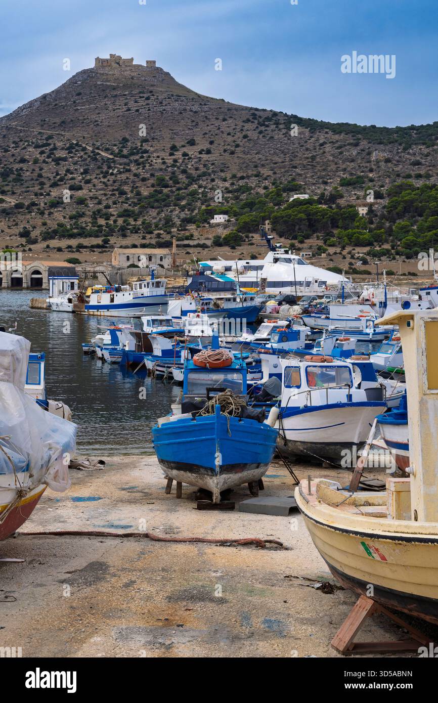 Le port de l'île de Favignana avec les vieux bateaux traditionnels de pêcheurs en bois et, en arrière-plan, le château de Santa Caterina, perché sur Banque D'Images