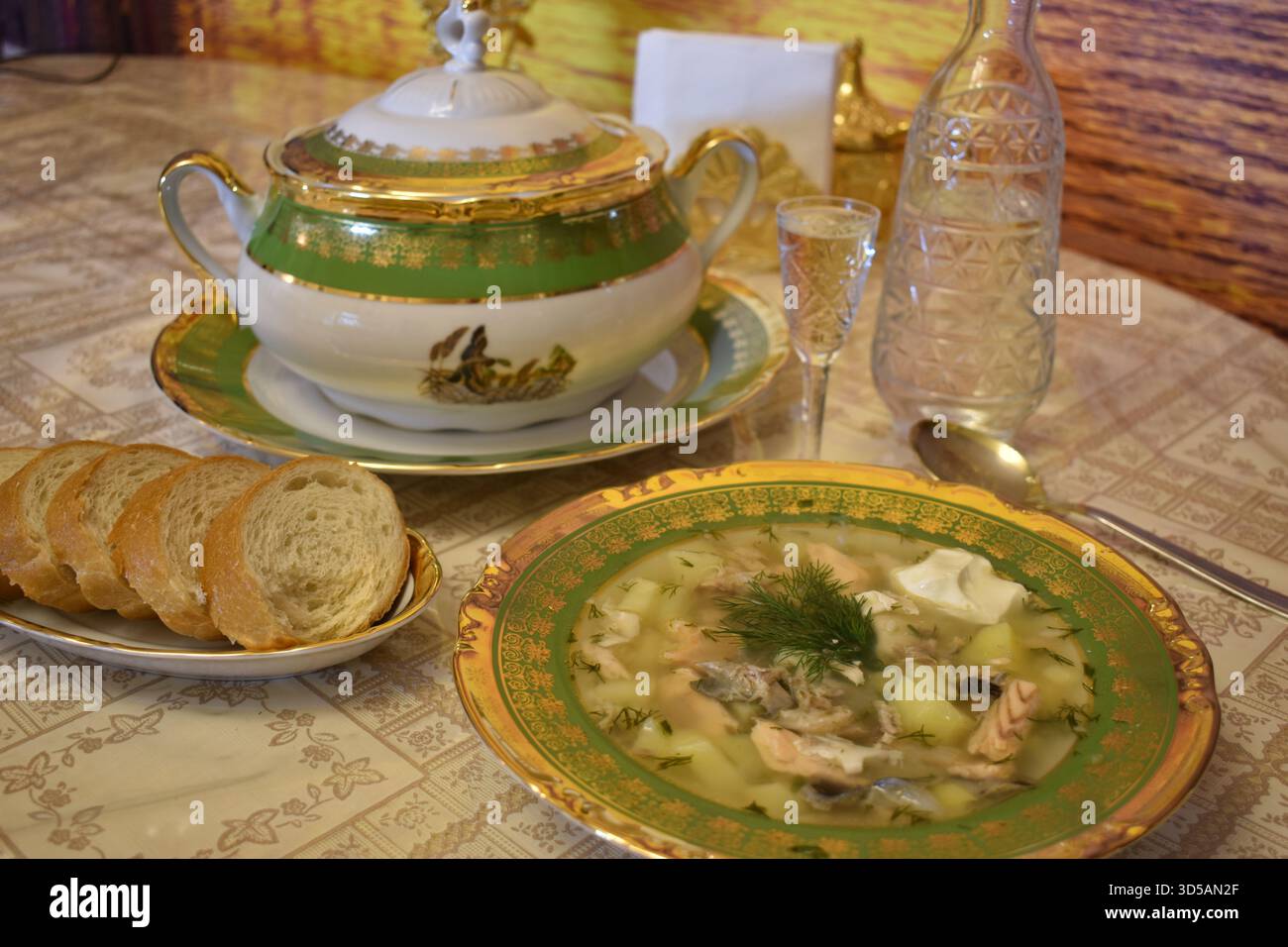 Élégante soupe de poisson et carafe en cristal de vodka servie dans de la vaisselle en porcelaine fine Banque D'Images