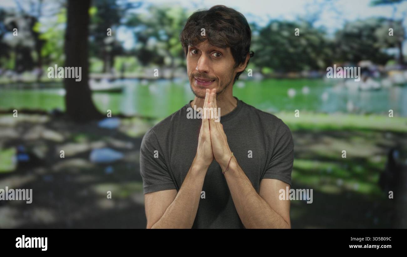 Homme pressant les mains ensemble dans un geste de prière sous la canopée verte dans la forêt ; espoir réflexion patience. Banque D'Images