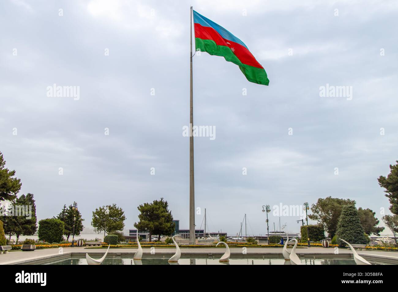 Bakou, Azerbaïdjan. La fontaine des cygnes ornée d'élégantes statues de cygne, tandis que le drapeau national azerbaïdjanais. Banque D'Images