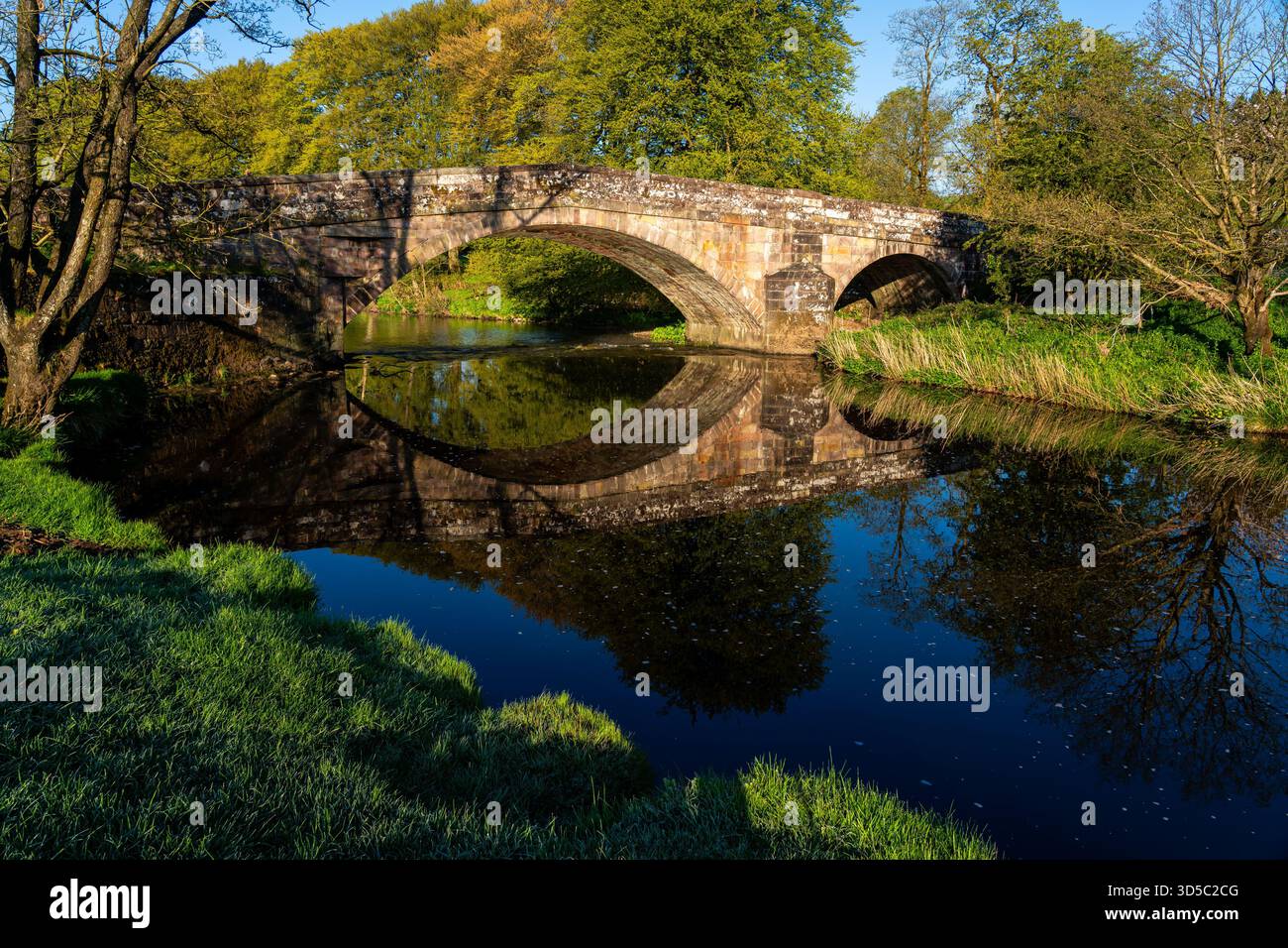 Pont en pierre voûté enjambant la rivière Hodder avec réflexion dans l'eau calme Banque D'Images