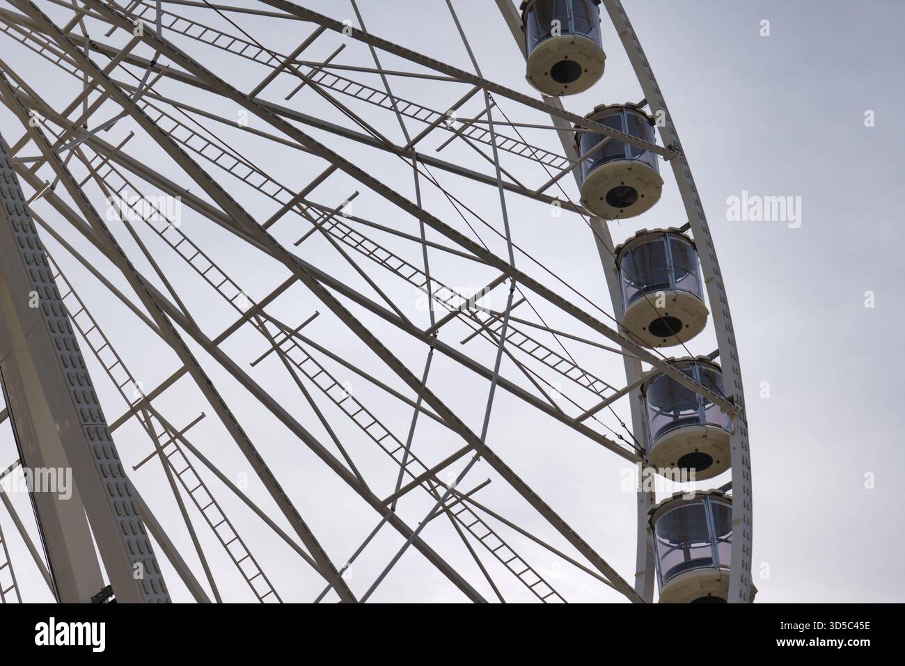 Une vue rapprochée d'une grande roue montre son cadre et ses cabines contre un ciel nuageux lors d'une foire. Banque D'Images