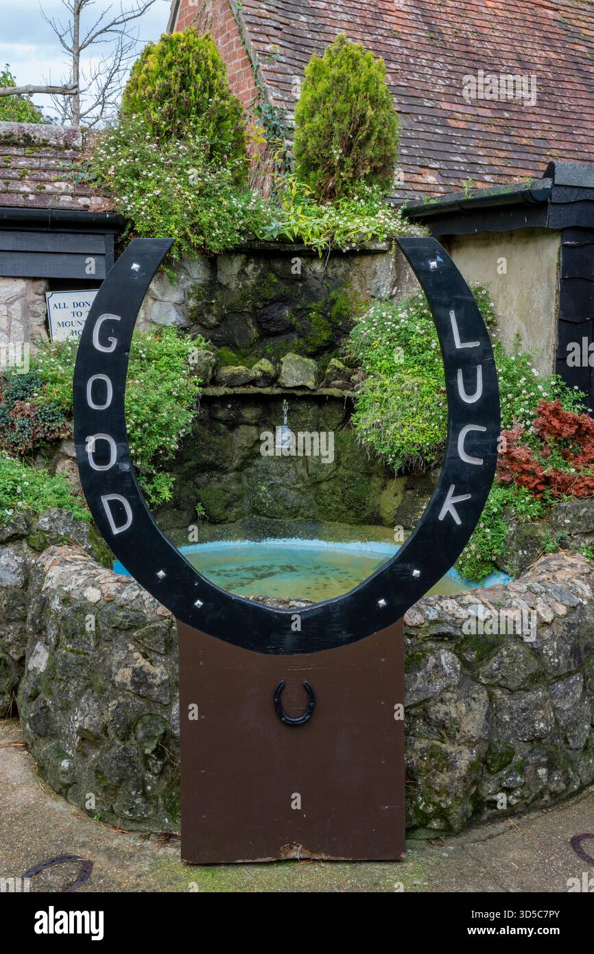 Grand fer à cheval chanceux avec les mots bonne chance autour du bord au bord d'un étang de vœux ou d'une piscine au Old Smithy dans Godshill Village, île de Wight. Banque D'Images