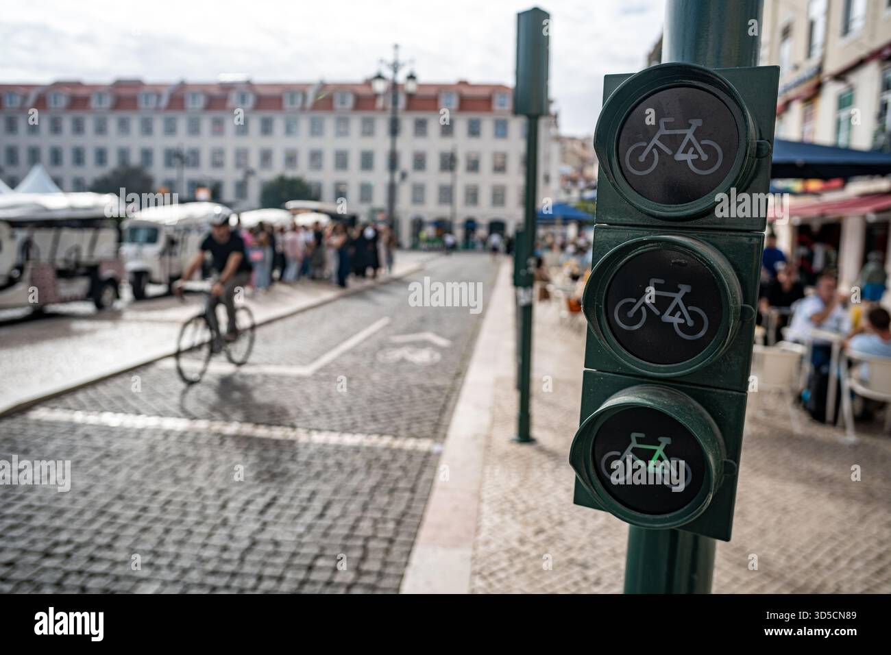Un cycliste Glovo passant par un feu vert sur la piste cyclable, Lisbonne- Portugal. Banque D'Images
