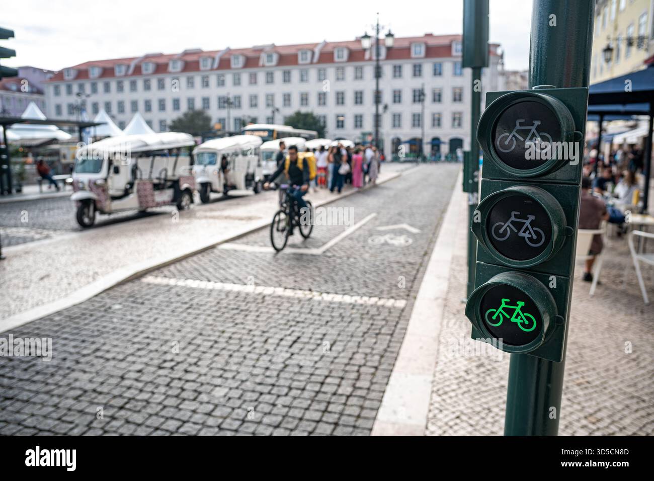 Un cycliste Glovo passant par un feu vert sur la piste cyclable, Lisbonne- Portugal. Banque D'Images