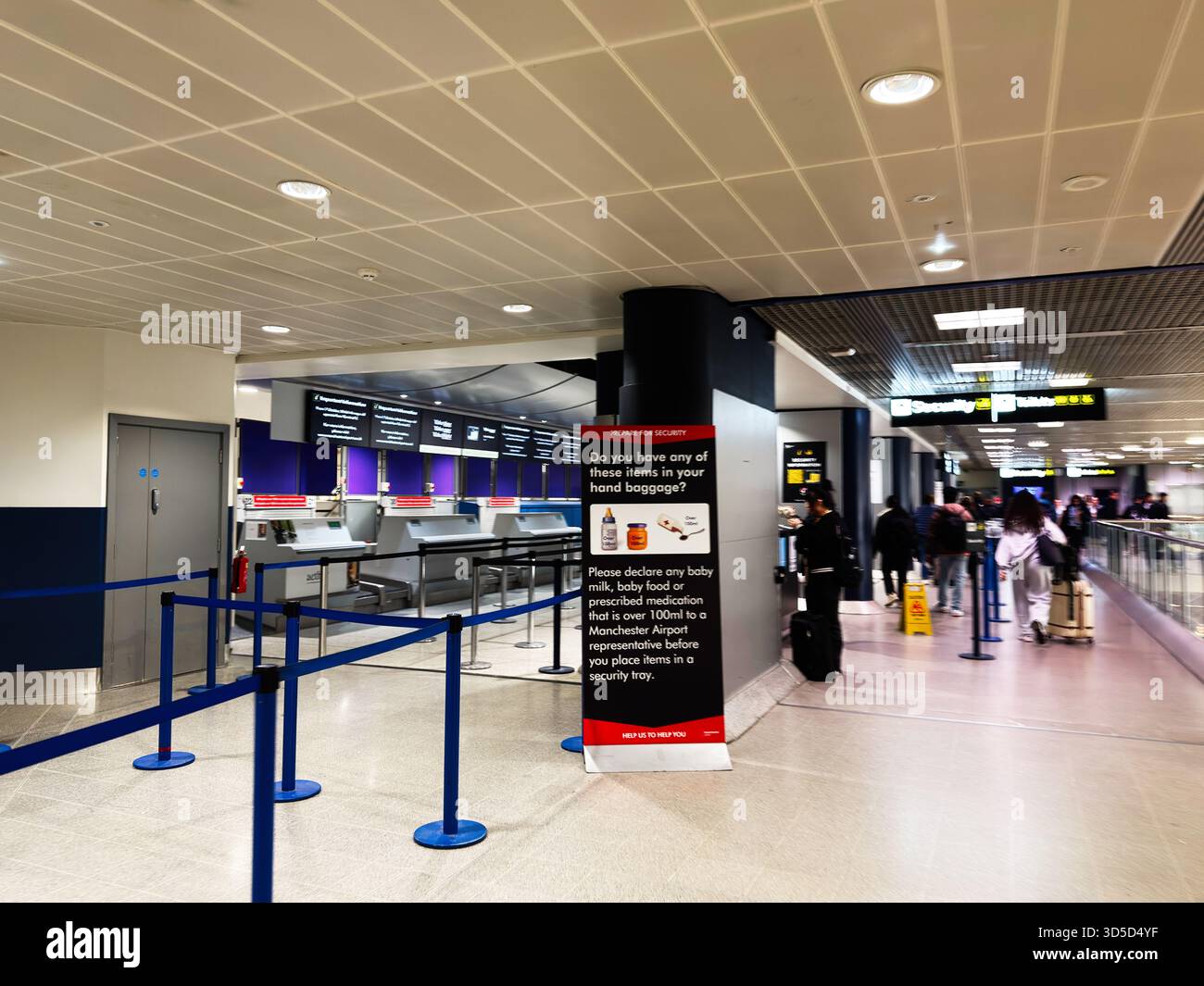 Manchester, Royaume-Uni - 04 octobre 2025 : les passagers font la queue aux guichets de sécurité de l'aéroport de Manchester, guidés par des panneaux et du personnel, en attente de contrôle. Banque D'Images