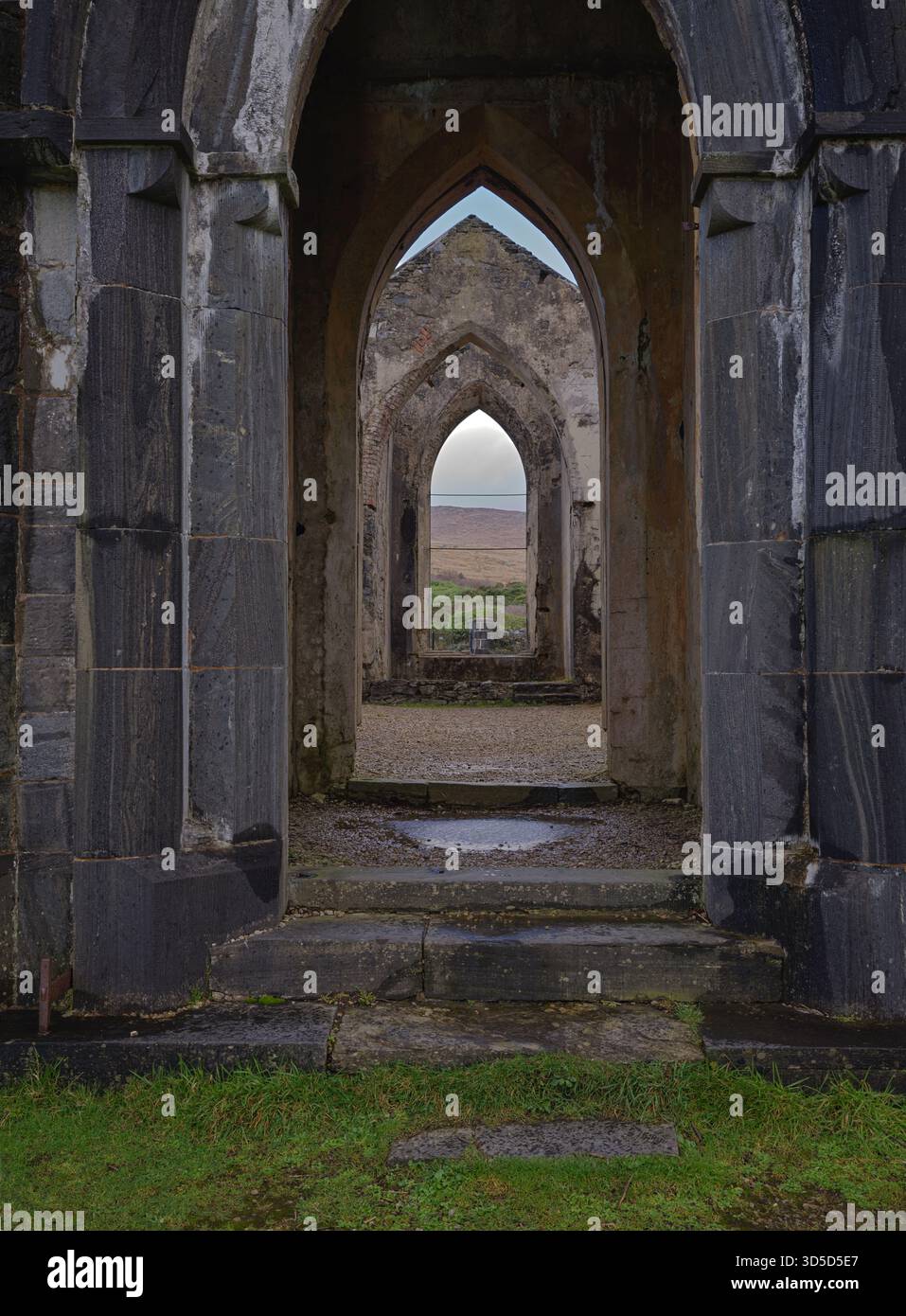 Ruines d'arche de pierre anciennes encadrant un paysage lointain à travers le couloir Archway de l'église Dunlewey dans le comté de Dunlewey Donegal Irlande 02/11/2025 Banque D'Images
