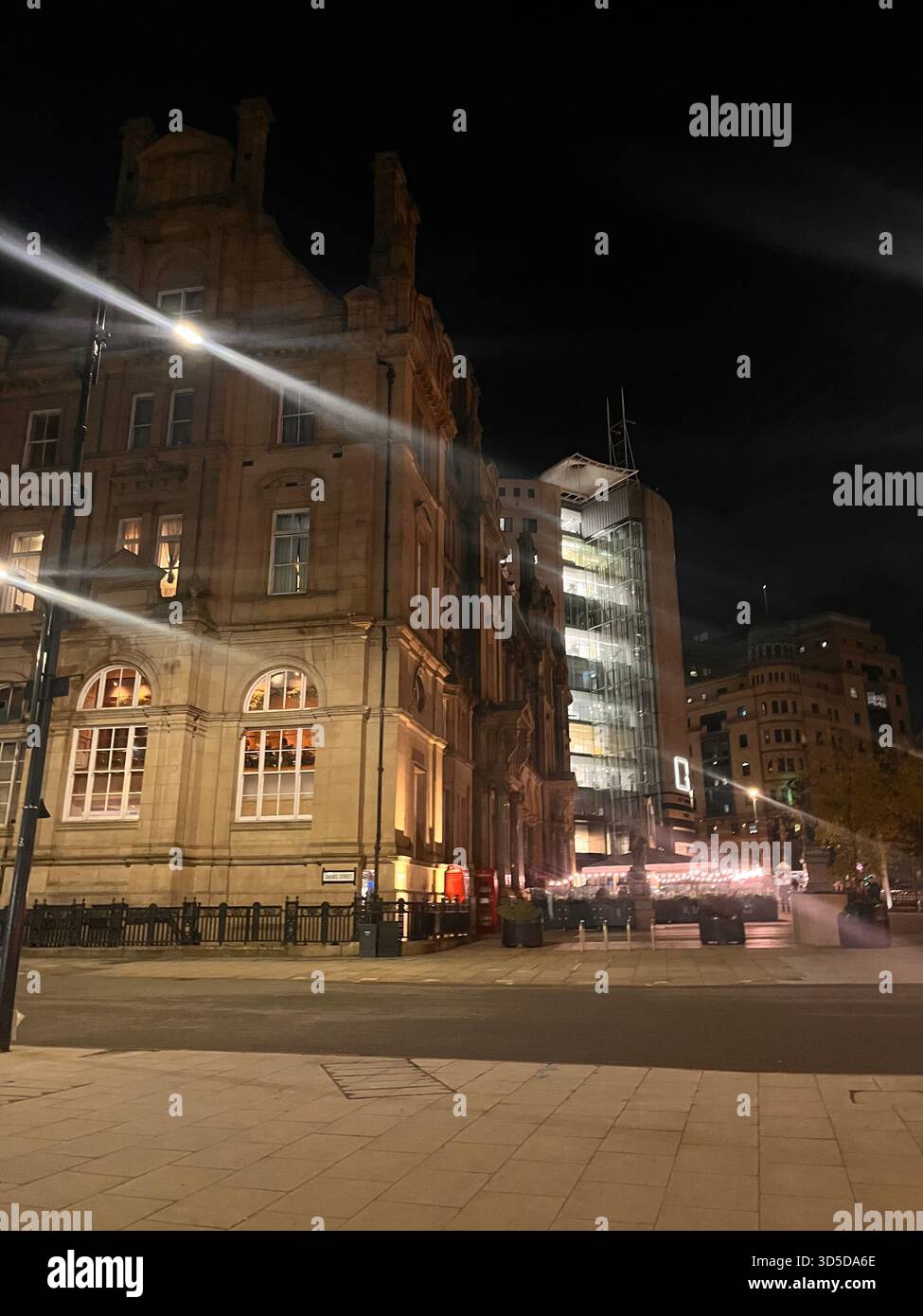 Bâtiment historique en pierre magnifiquement éclairé à Leeds, West Yorkshire, Angleterre, photographié la nuit avec des sentiers de feux de circulation - Image de stock capturée avec un smartphone