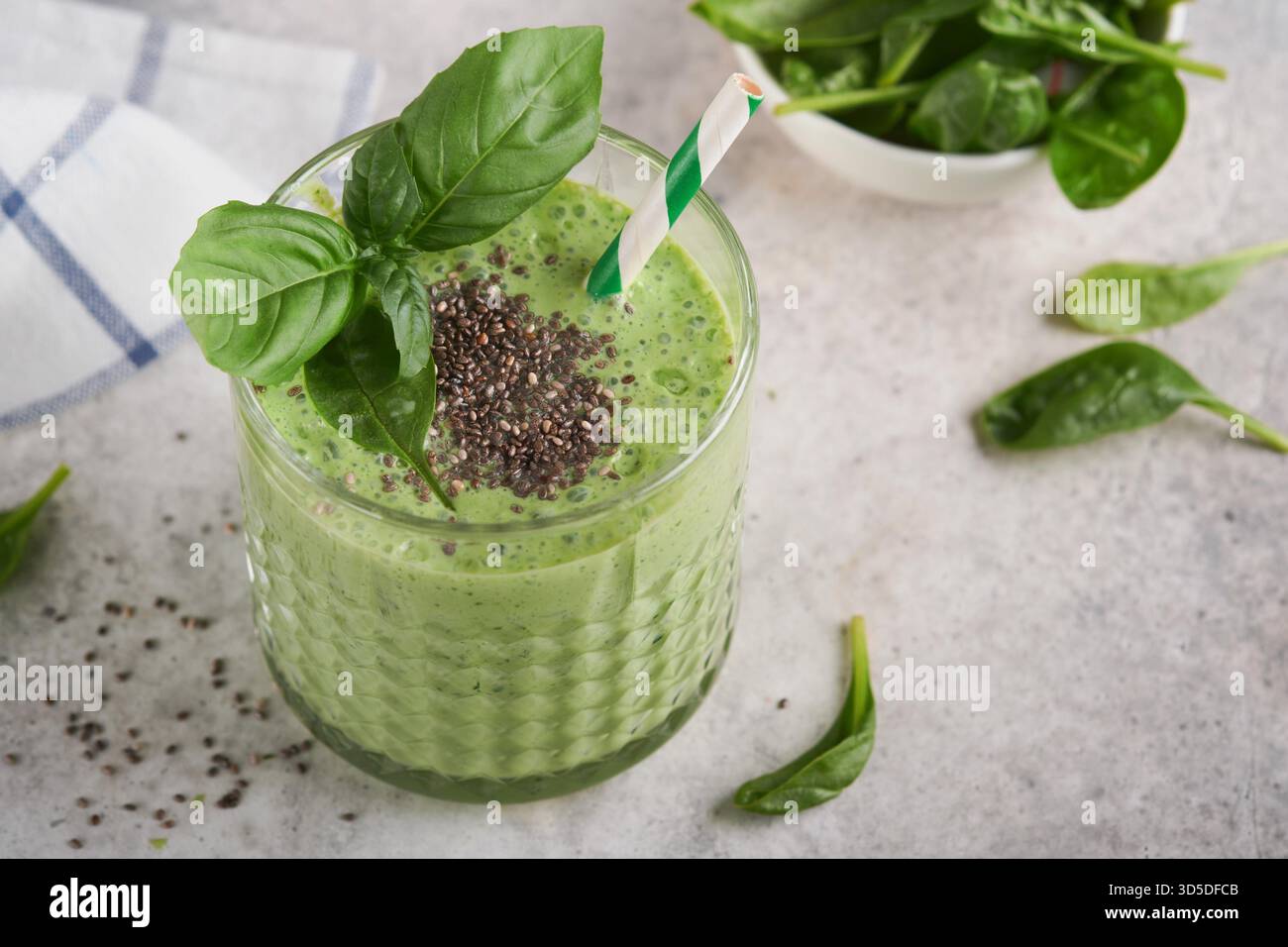 Smoothie aux épinards vert sain. Smoothie végétalien ou milkshake à partir d'épinards, de bananes et de graines de chia sur fond de table en béton gris. Manger propre, régime alcalin. Vue de dessus. Maquette. Banque D'Images