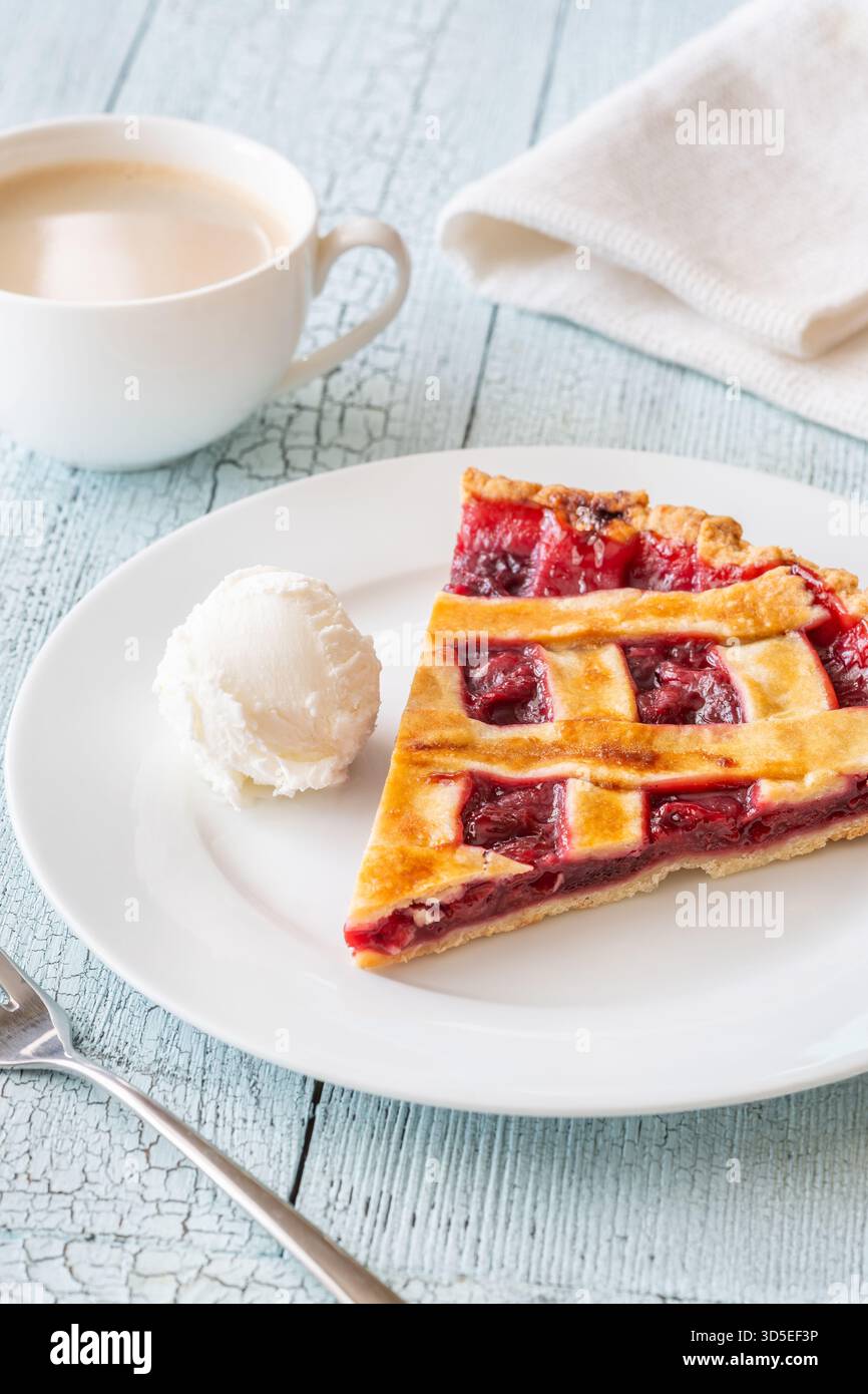 La tarte chaude et la crème glacée fraîche se marient parfaitement avec le café à la vapeur dans une lumière douce Banque D'Images