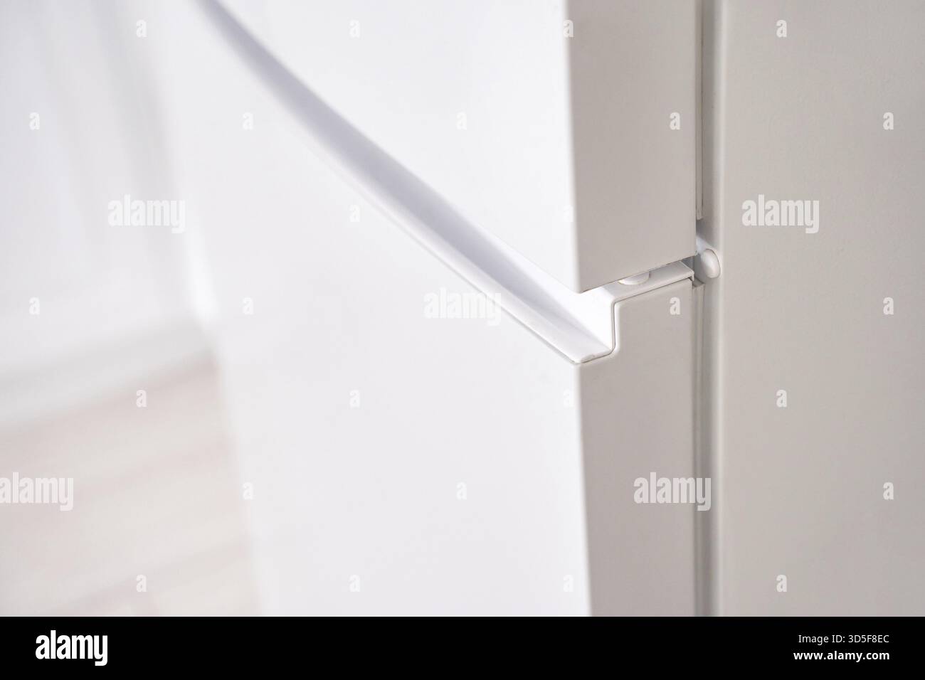 Gros plan de la porte blanche moderne de réfrigérateur avec conception de poignée sans couture dans le cadre lumineux de la cuisine Banque D'Images