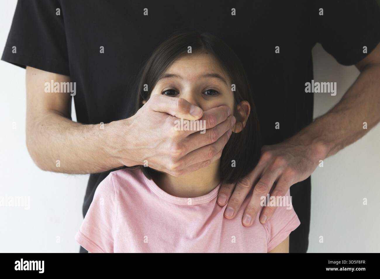 La main masculine couvre la bouche de l'enfant fille de 7-8 ans, gros plan, abus d'enfant, concept de violence domestique, protection de l'enfant Banque D'Images